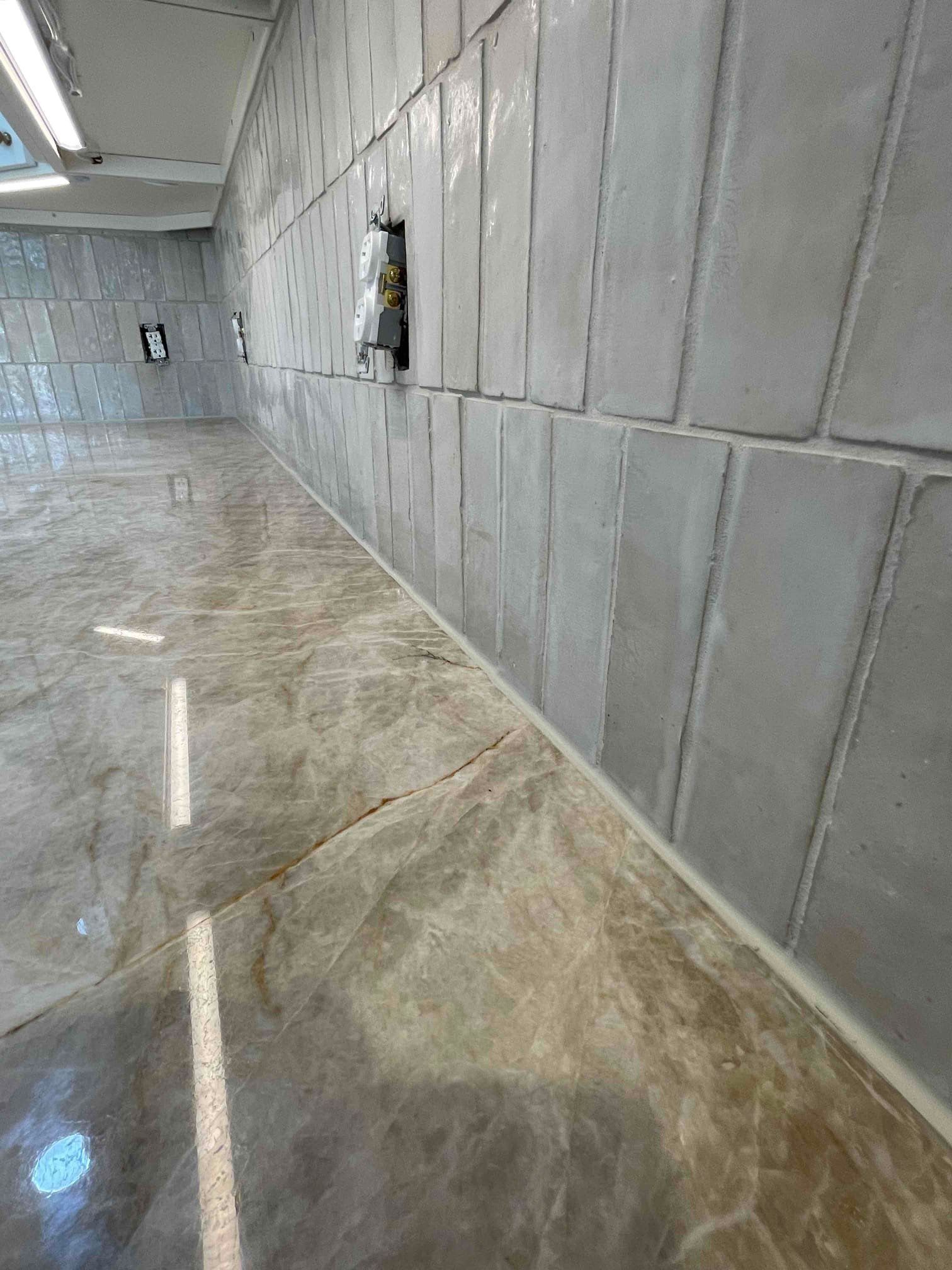 Polished quartz countertop with warm veining beside a vertically stacked pale tile wall